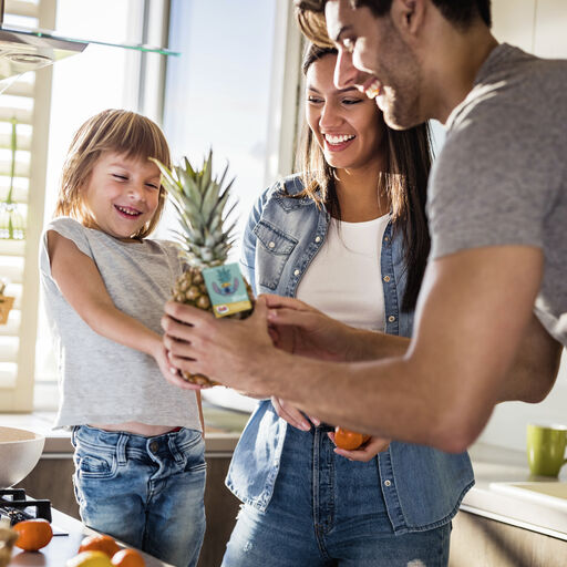 A small family holding a Dole Pineapple